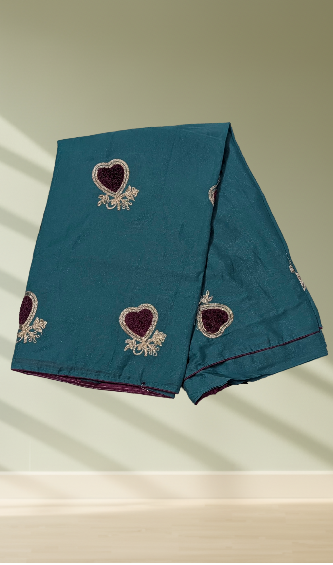 Teal blue heart embroidered georgette saree with white thread work and burgundy velvet centers